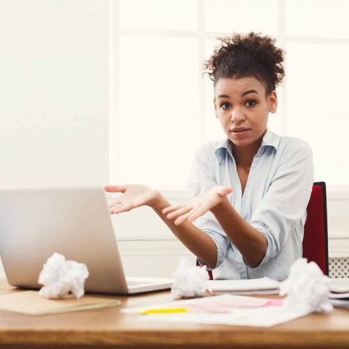 Business woman at a loss working on laptop at office African-american business woman at a loss working on laptop at office. Businesswoman sitting at her working place, copy space